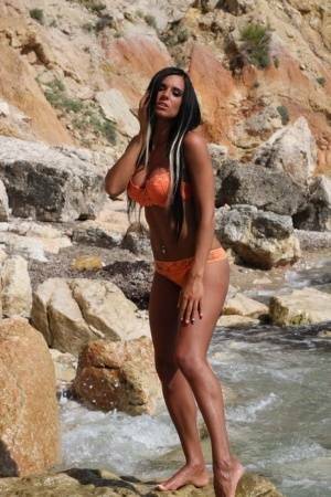 Leggy teen with long hair takes off her bikini in a fast moving stream on myfans.pics