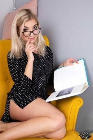 Geeky blonde Amelia undresses on a chair before playing with her shaved pussy on myfans.pics